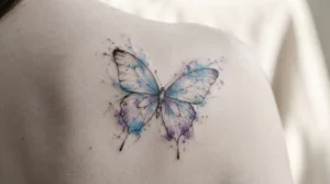 watercolor butterfly tattoo with blue and purple paint splashes on shoulder blade